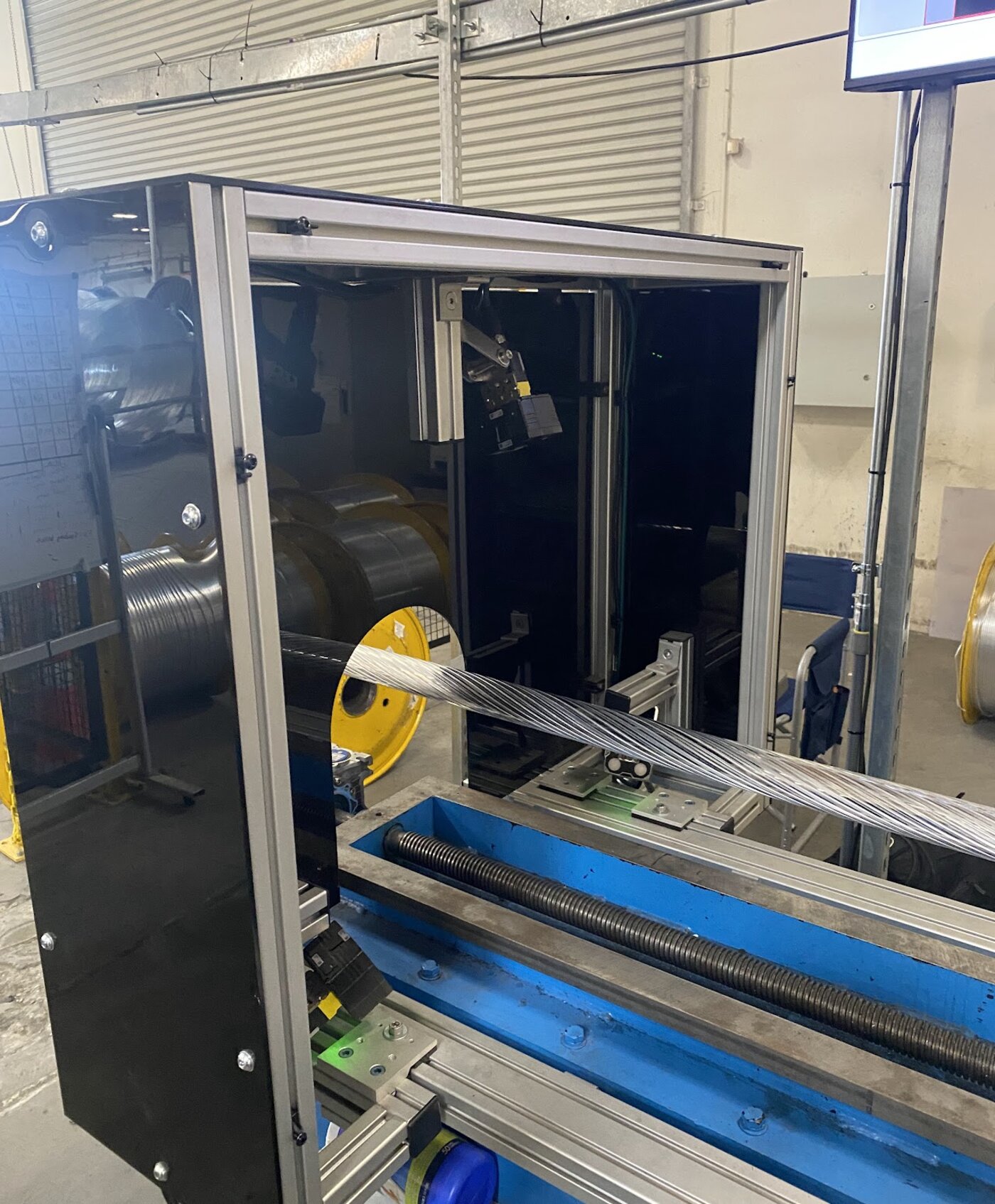 Factory-floor photo of the cable inspection machine with cable spool