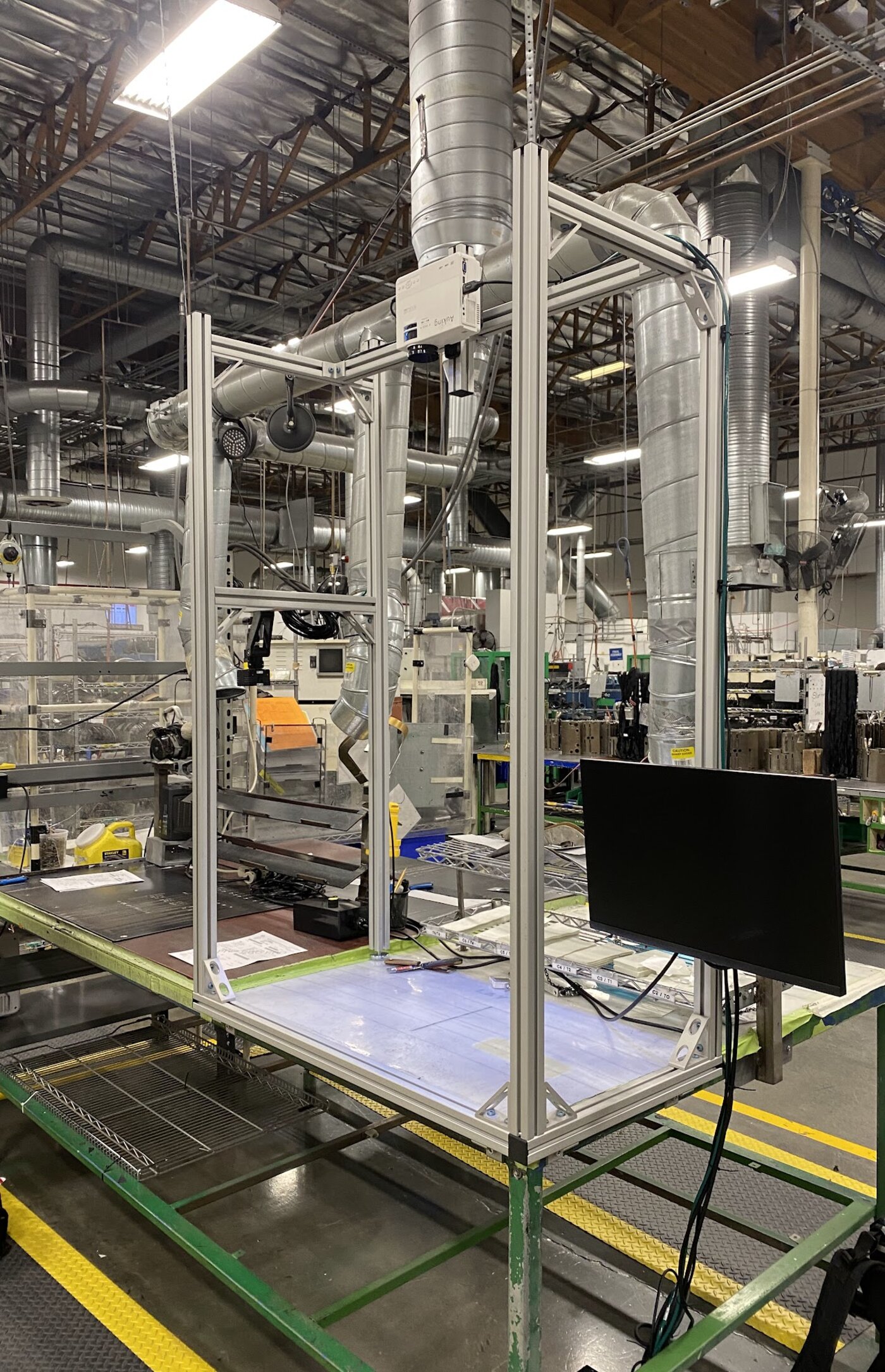 Factory-floor photo of the camera/projector rig installed on the production floor