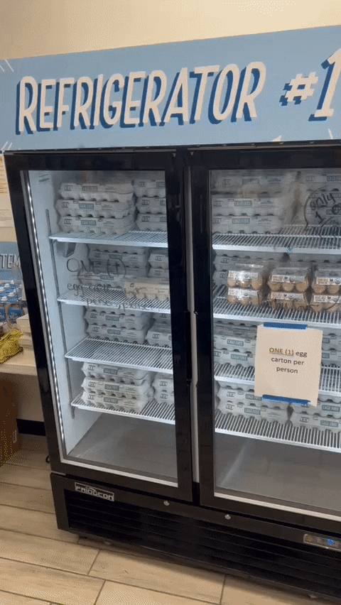 Refrigerator #1 with egg cartons and a one-carton-per-person sign